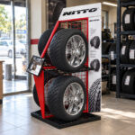 Lastik showroomunda raf yanında duran NITTO panolu metal otomobil lastiği standı.